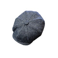 A mid blue/gray textured tweed flat cap with a buttoned center top, photographed from a top-down angle on a solid white background.